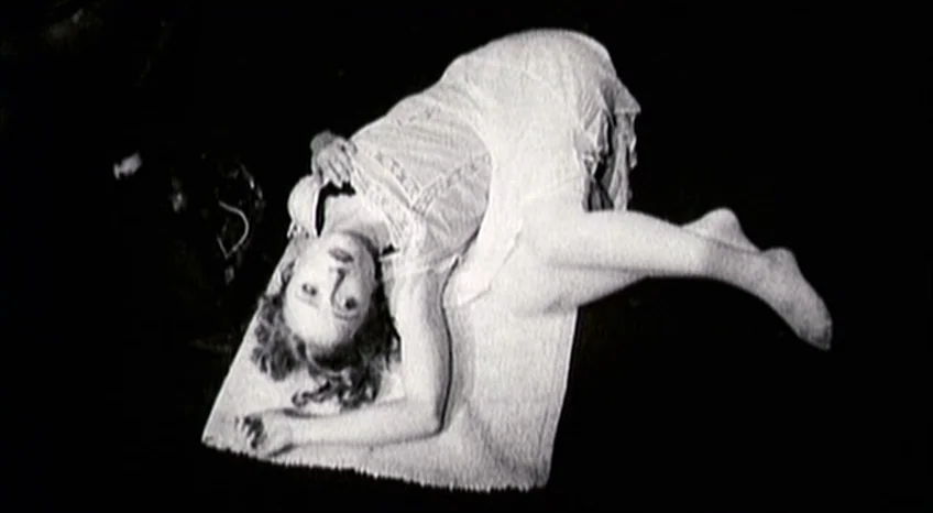 Brand Upon the Brain! (2006) movie still: fullbody — A dark, featureless environment contains a small white rectangular rug on the floor. A woman in…