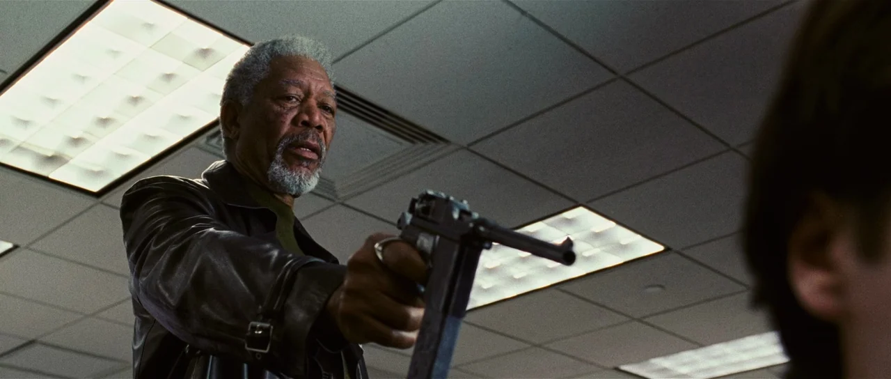 Wanted (2008) movie still: medium — An interior office space features a grid of white fluorescent ceiling panels. A man points a handgun toward…