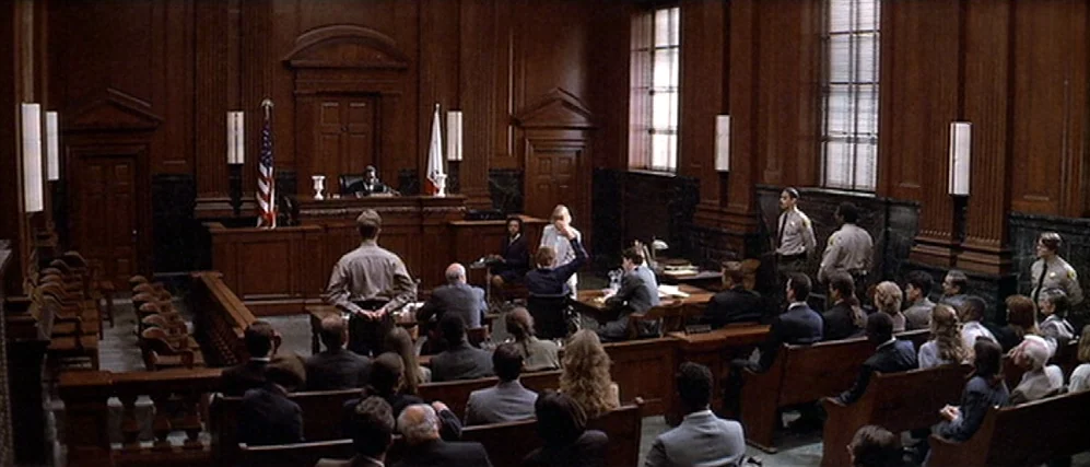 The People vs. Larry Flint (1996) movie still: wide — A spacious wood-paneled courtroom features pews for observers and a central elevated judge…