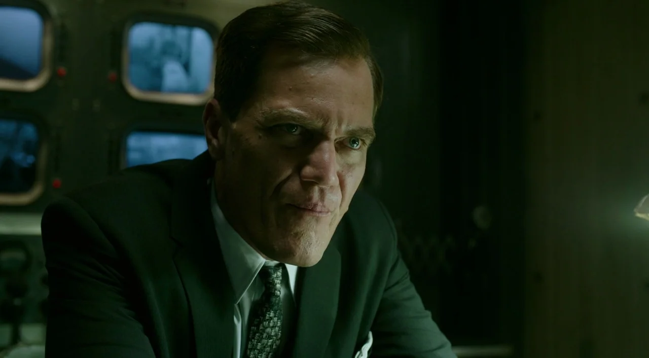 The Shape of Water (2017) movie still: closeup — A dimly lit room features a bank of small security monitors in the background. A middle-aged man in…