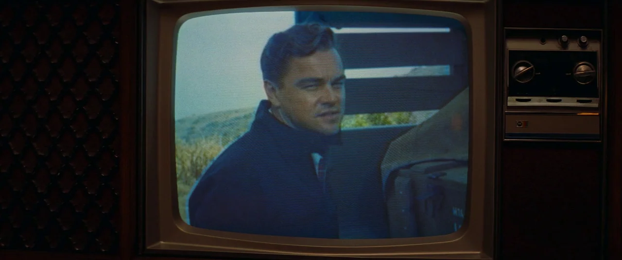Once Upon a Time… In Hollywood (2019) movie still: closeup — A man appears on a vintage wooden television set displaying a grainy broadcast. The man…