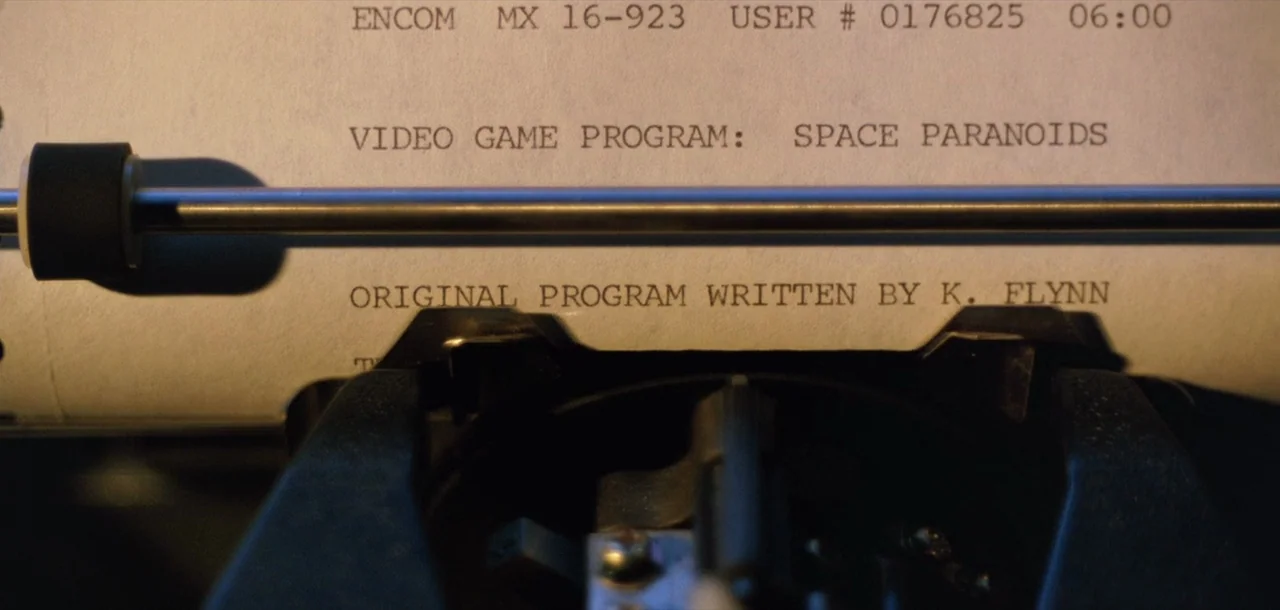 Tron (1982) movie still: closeup — A close-up view of a typewriter platen with white paper containing printed computer data. The document displays…