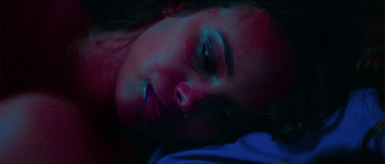 68 Kill (2017) movie still: closeup — A dark bedroom interior with colored lighting bathing a person's face. The woman lies horizontally on a pillow…