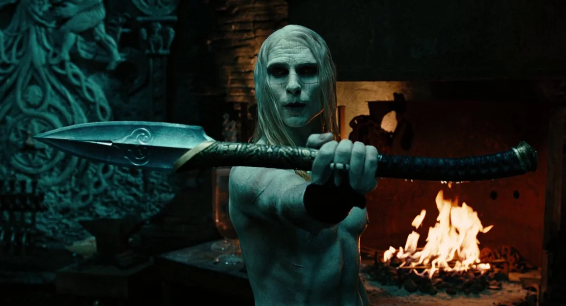 Hellboy II: The Golden Army (2008) movie still: medium — A dark stone chamber features an intricate relief wall carving and an open fireplace. A…
