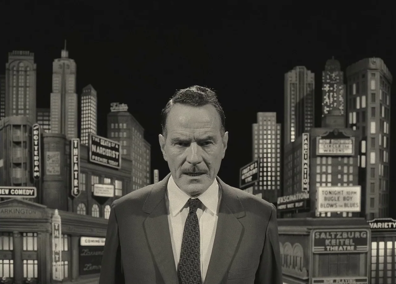 Asteroid City (2023) movie still: medium — A man stands before a stylized miniature city set with prominent neon-style building signage. He faces…