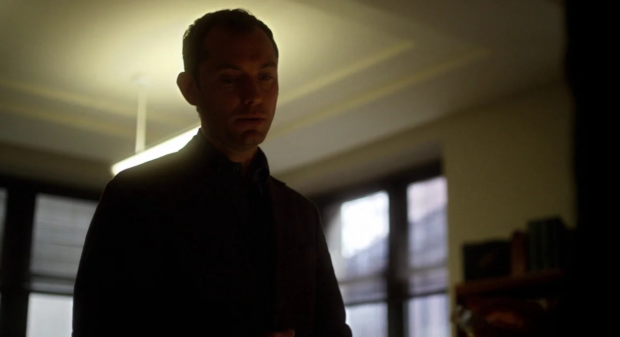 Side Effects (2013) movie still: medium — An office interior features a wooden bookshelf and large windows with closed blinds. A man in a dark suit…