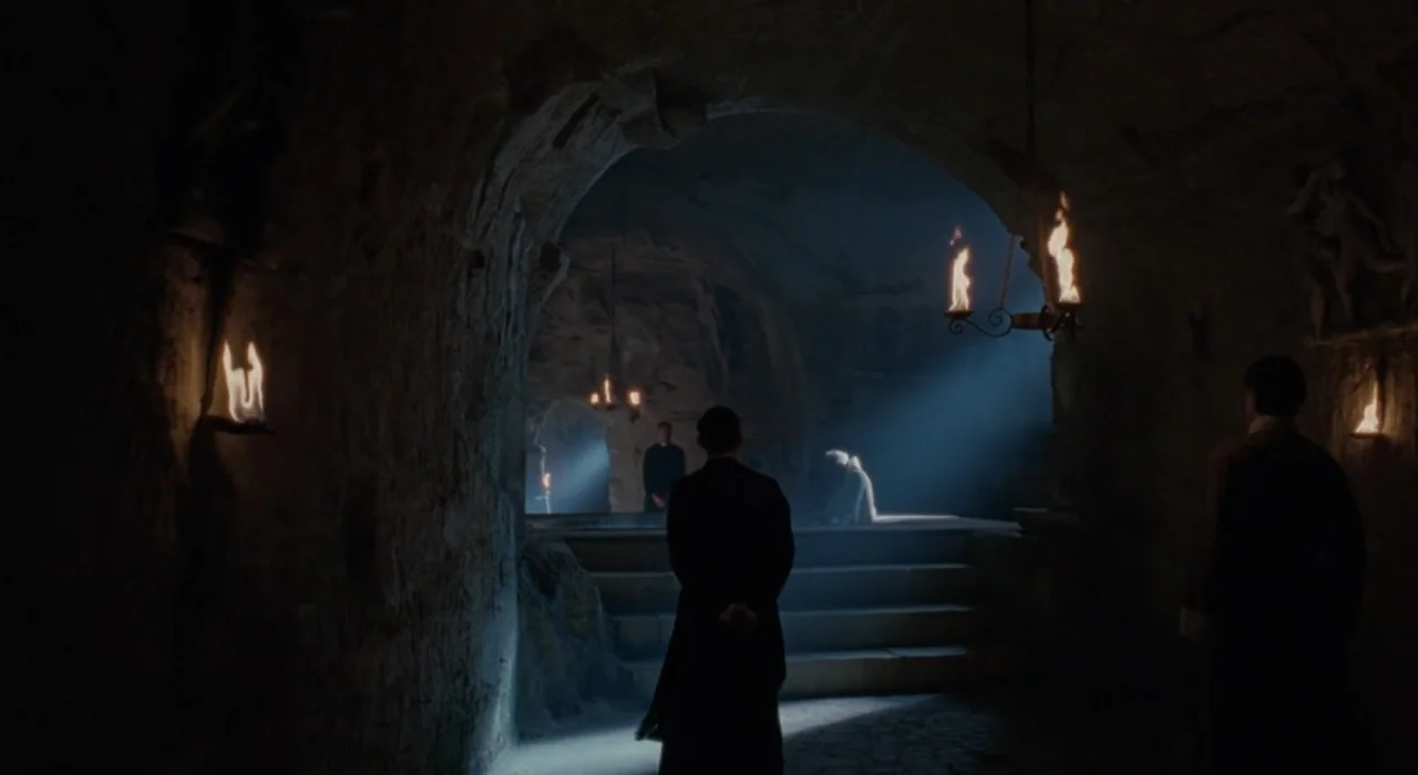 The Great Beauty (2013) movie still: wide — A dark subterranean stone vaulted chamber features arched doorways and uneven rock walls. A man in a…