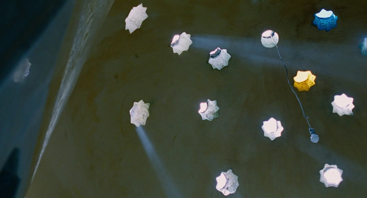 Aftersun (2022) movie still: establishing — A curved masonry dome features multiple star-shaped cutouts arranged across its dark surface. Bright…