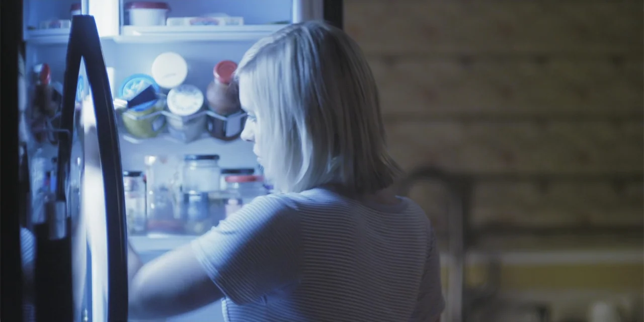 Stalked by My Doctor: A Sleepwalker's Nightmare (2019) movie still: medium — A dimly lit kitchen features a woman standing before an open,…