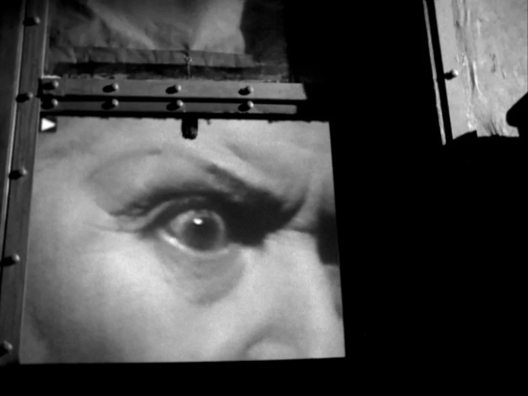 My Winnipeg (2007) movie still: closeup — A square projection window displays a close-up of a human eye in high contrast. The surrounding area of…