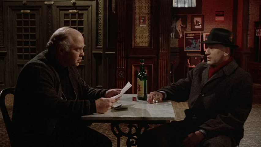 Once Upon A Time In America (1984) movie still: medium — A dimly lit pub interior with dark wood wainscoting and a marble-topped table. Two men sit…