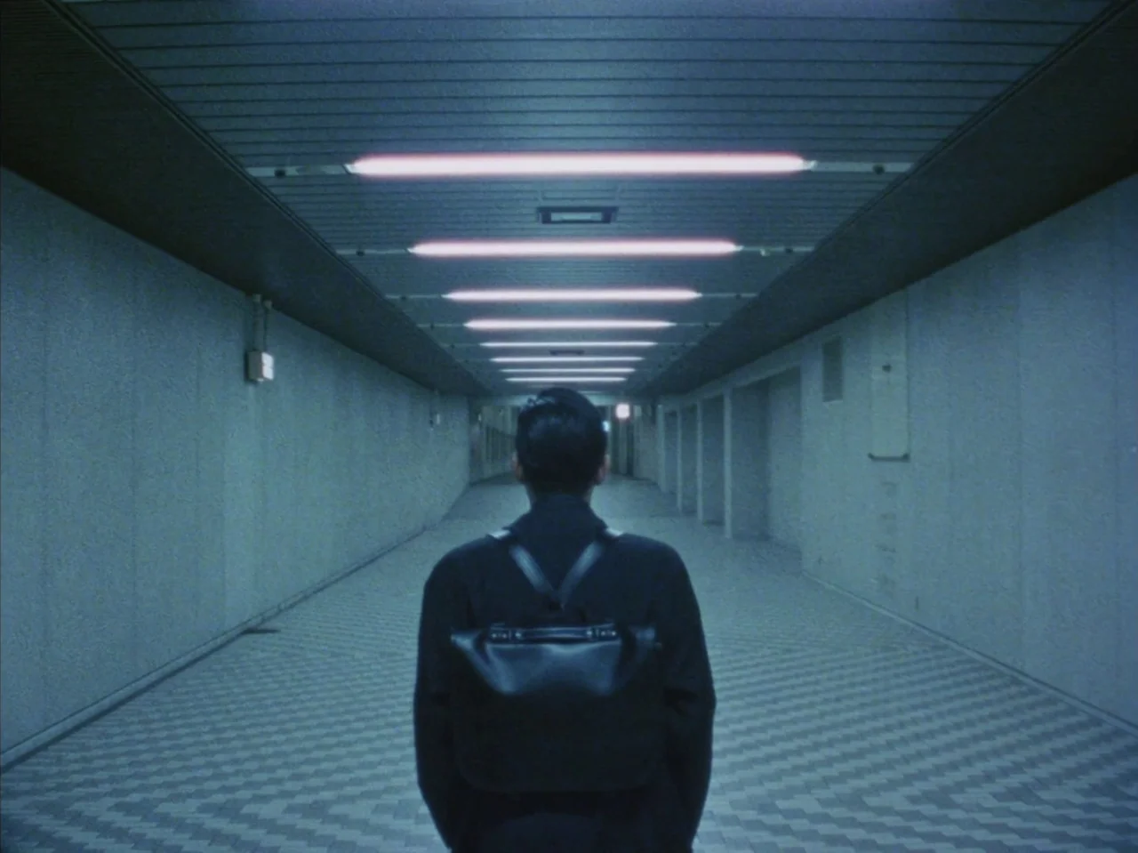 Tetsuo II: Body Hammer (1992) movie still: medium — A long, sterile concrete pedestrian tunnel features a symmetrical grid floor and fluorescent…