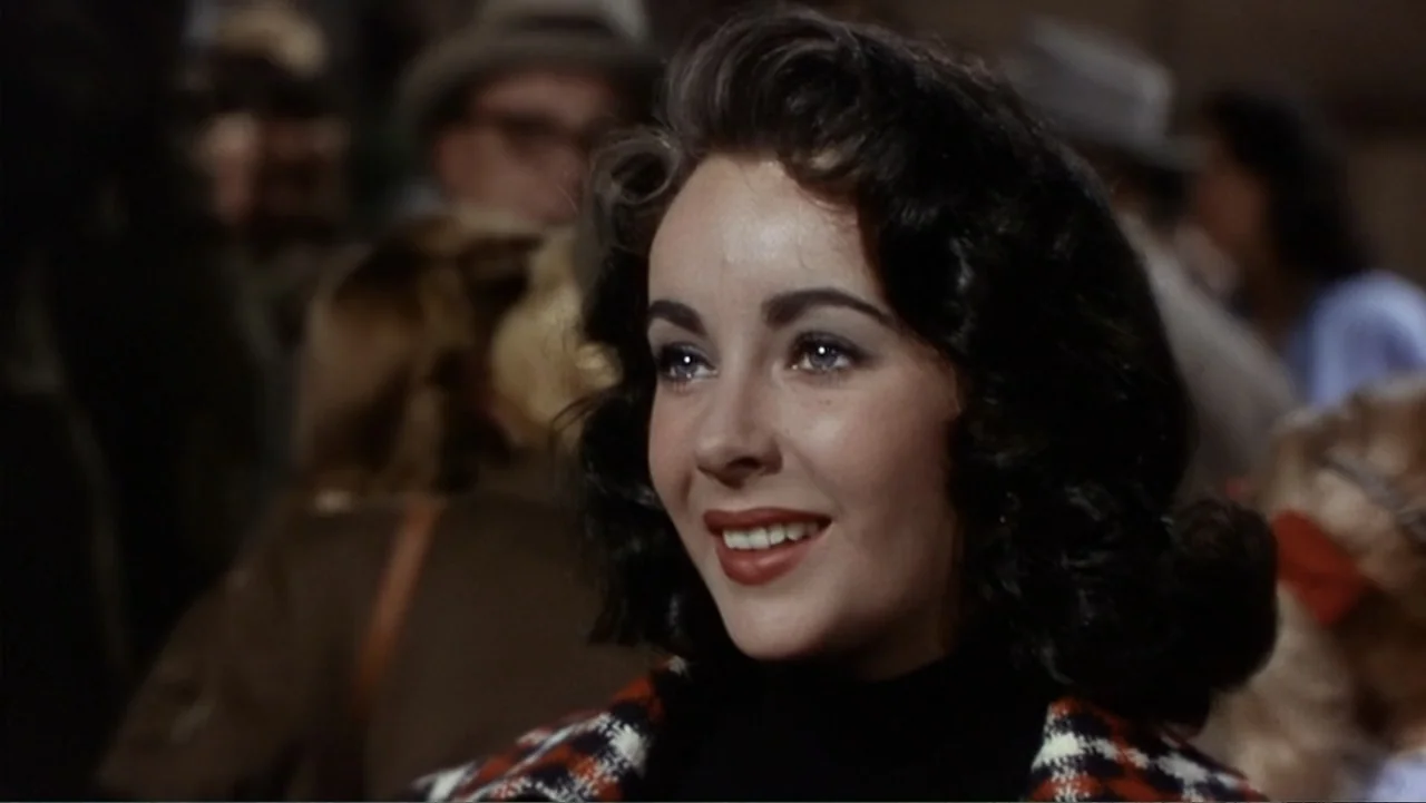 Elizabeth Taylor: The Lost Tapes (2024) movie still: closeup — A crowded outdoor public space filled with blurry figures in 1950s period attire. A…