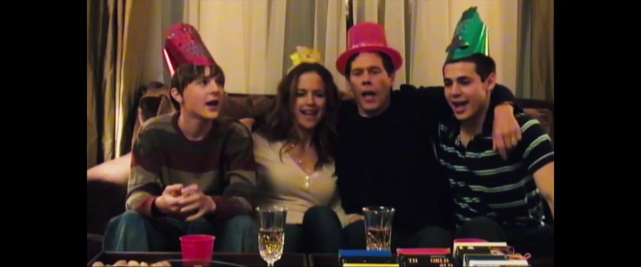 Death Sentence (2007) movie still: medium — Four people wearing colorful paper party hats sit together on a couch at night. They are looking forward…