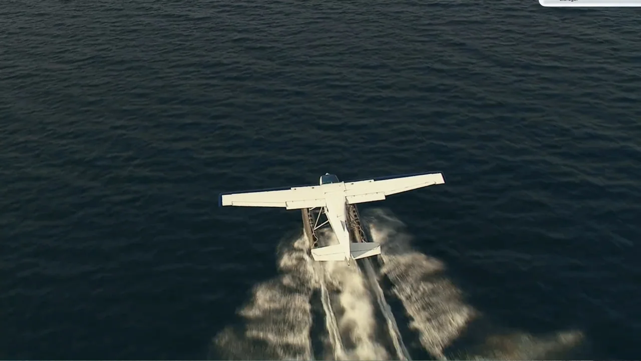 National Parks Adventure (2016) movie still: wide — A vast expanse of deep blue water surrounds a small white seaplane. The aircraft moves forward…