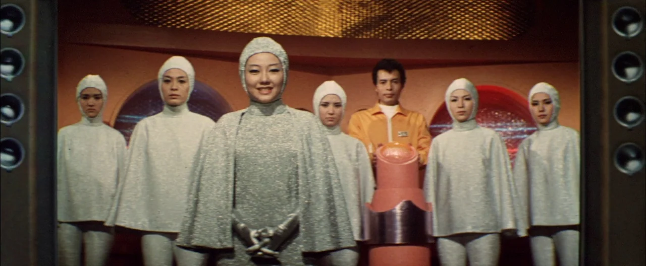 Destroy All Monsters (1968) movie still: medium — A spaceship bridge features orange walls and circular viewing ports showing starry space. A group…