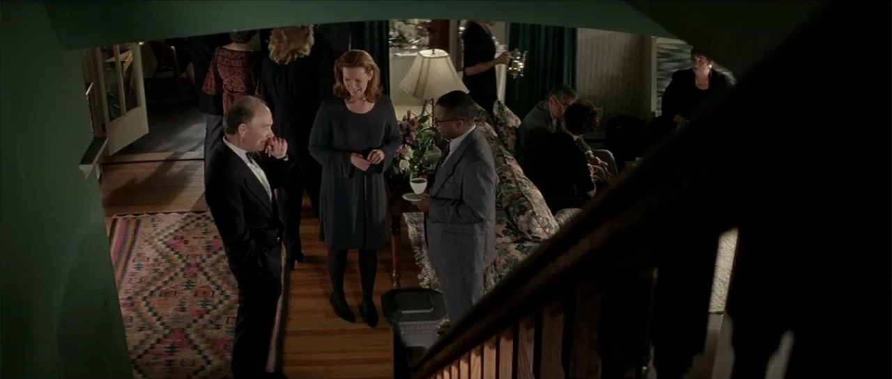 Moonlight and Valentino (1995) movie still: medium — A well-lit residential interior features a group of people standing on hardwood floors. Three…
