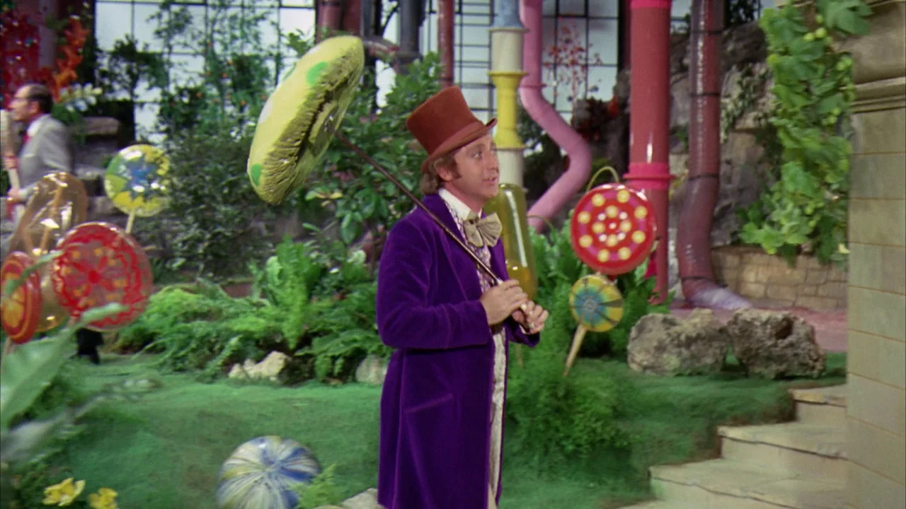 Willy Wonka & the Chocolate Factory (1971) movie still: fullbody — An indoor garden area features large synthetic candy props and stylized foliage.…