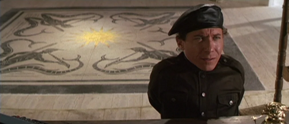 Boom! (1968) movie still: medium — A study floor features a large intricate tile mosaic of a sun and serpents. A man in a dark military uniform sits…