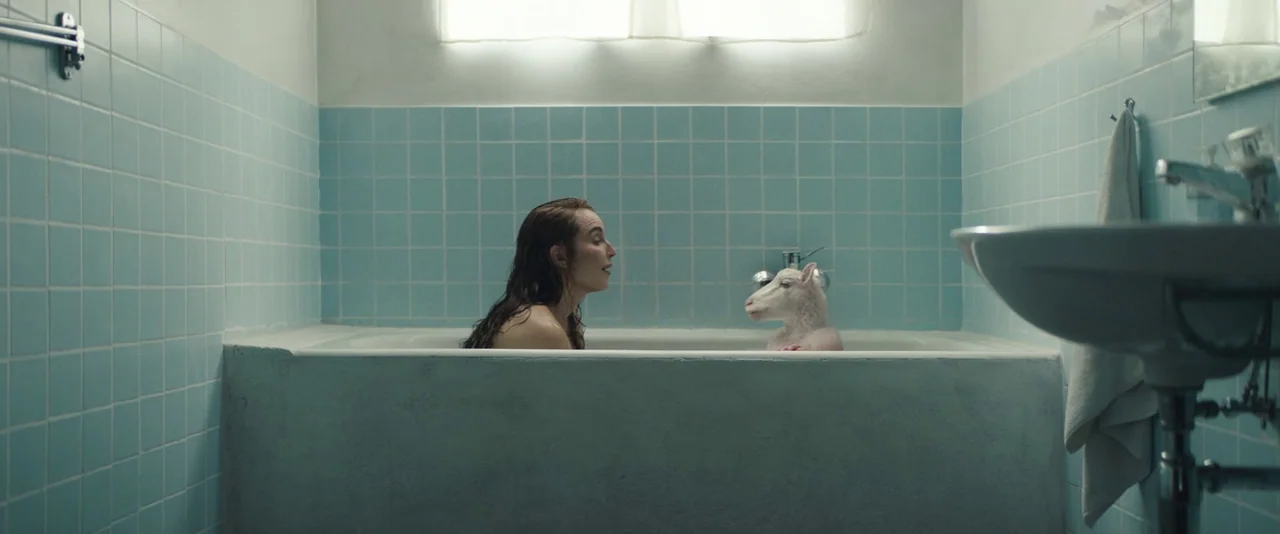 Babel (2006) movie still: wide — A bathroom features blue-tiled walls, a white ceramic bathtub, and a pedestal sink. A woman sits in the tub…