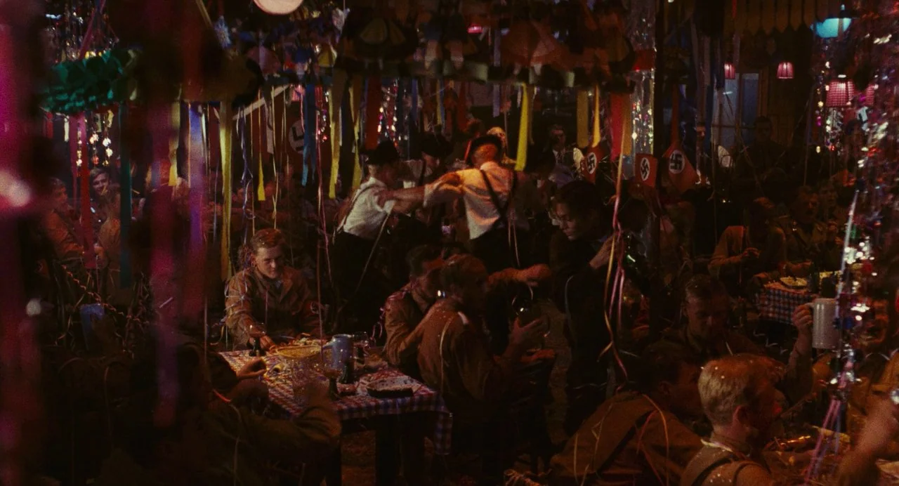 The Damned (1969) movie still: wide — A dark, crowded room is filled with colorful paper streamers and festive hanging decorations. Soldiers in…