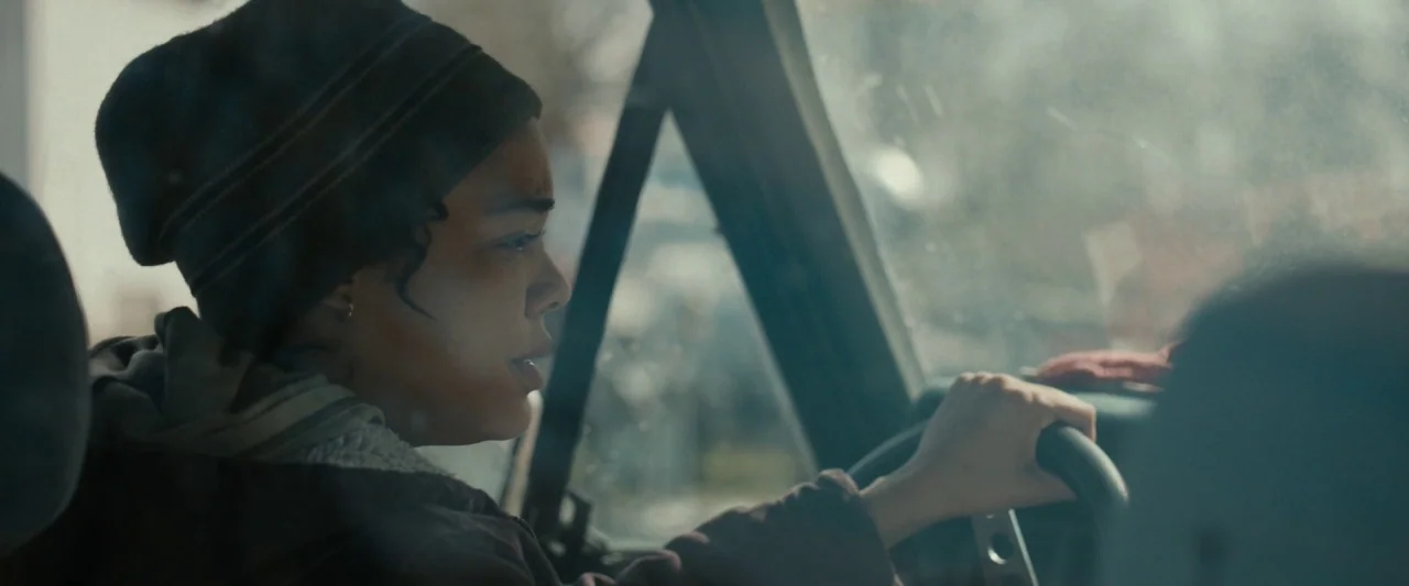 Little Woods (2018) movie still: medium — A person sits inside the driver seat of a vehicle during the day. The subject grips the steering wheel and…