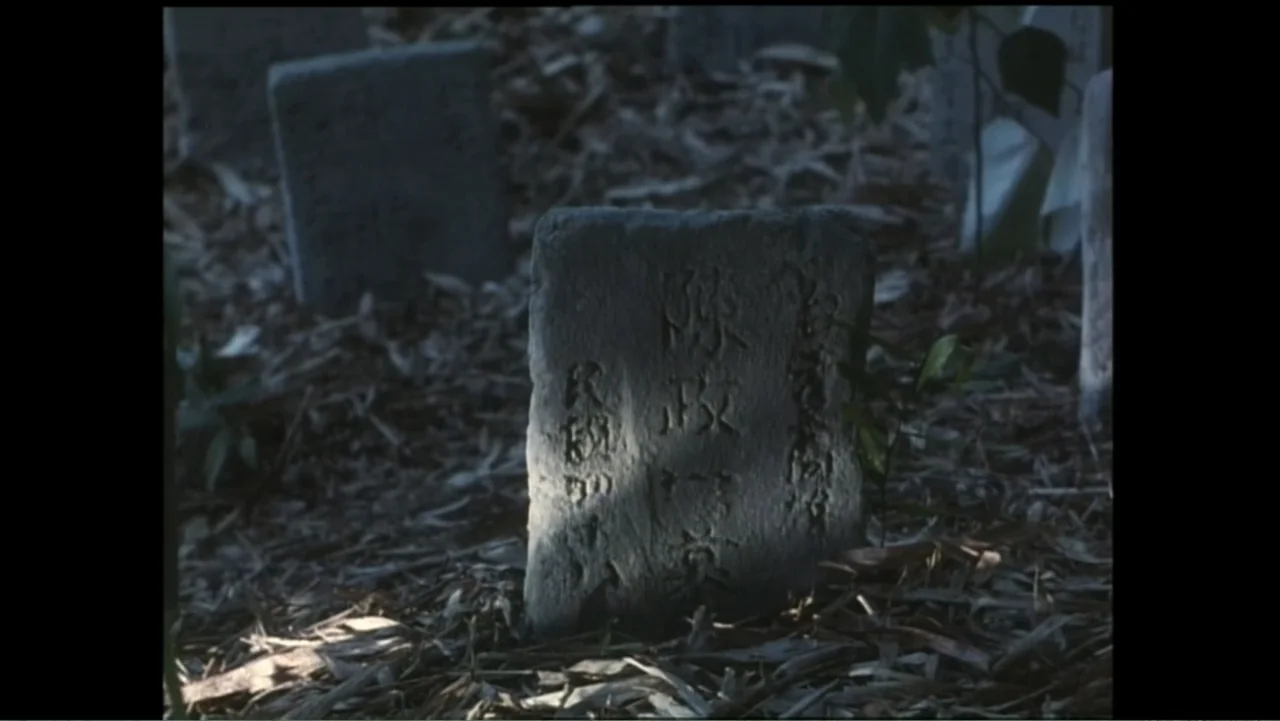 Flowers of Taipei: Taiwan New Cinema (2014) movie still: closeup — A stone grave marker with Chinese inscriptions stands among dry leaves in a…