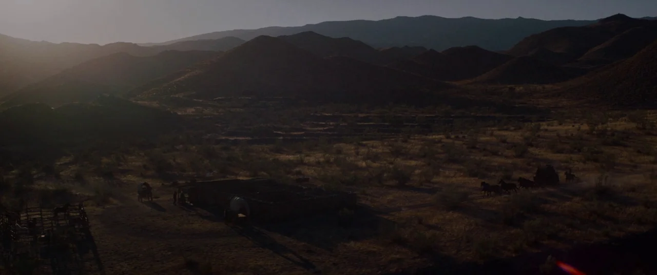 The Sisters Brothers (2018) movie still: establishing — A vast arid desert landscape is surrounded by jagged mountains under a golden sunset.…