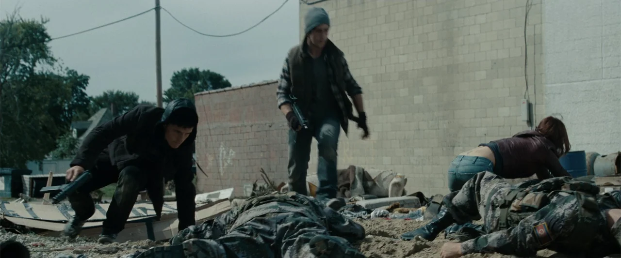 Red Dawn (2012) movie still: wide — A desolate urban lot features broken brick walls and piles of scattered debris. Three armed individuals…