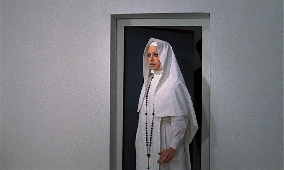 Successive Slidings of Pleasure (Glissements progressifs du plaisir) (1974) movie still: medium — A woman dressed as a nun stands in a doorway set…