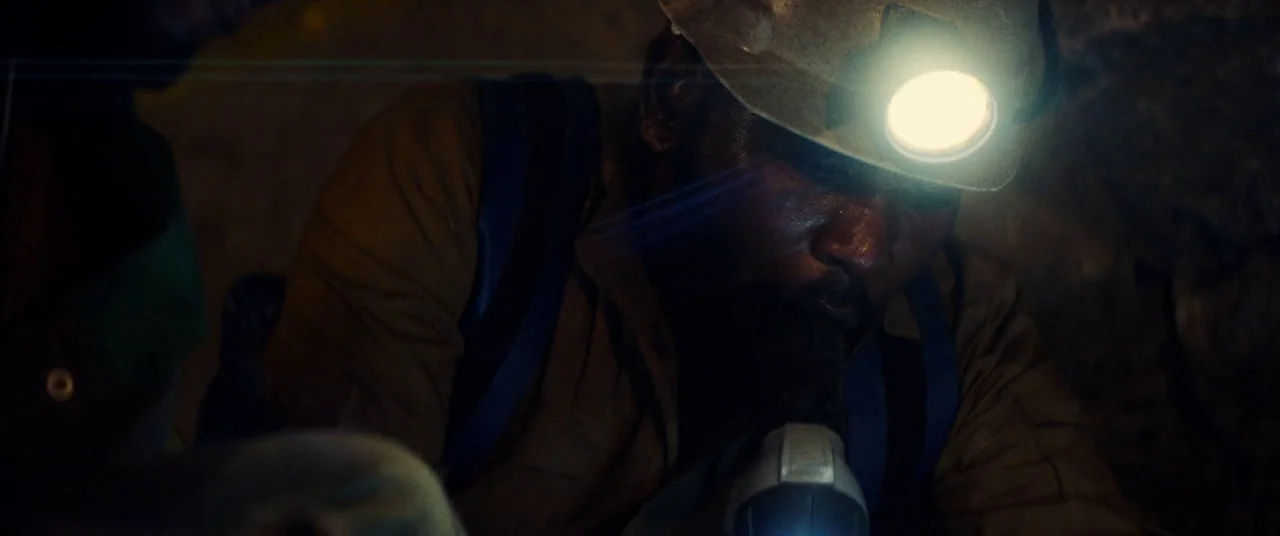 Uncut Gems (2019) movie still: medium — A dark, cramped stone tunnel with rough surfaces is illuminated by a single light. A man wearing a headlamp…