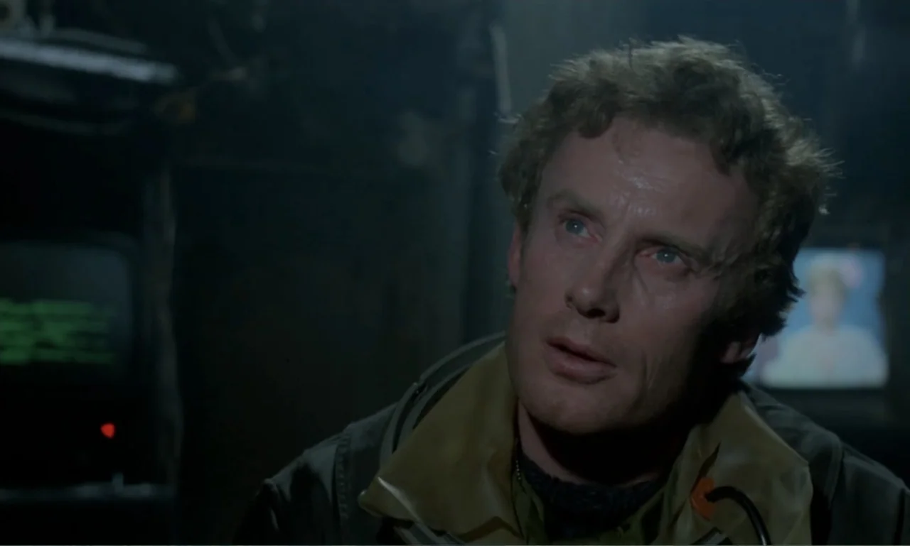 Ga-ga: Glory to the Heroes (1986) movie still: closeup — A dimly lit, cramped cabin containing dark industrial surfaces and glowing electronic…