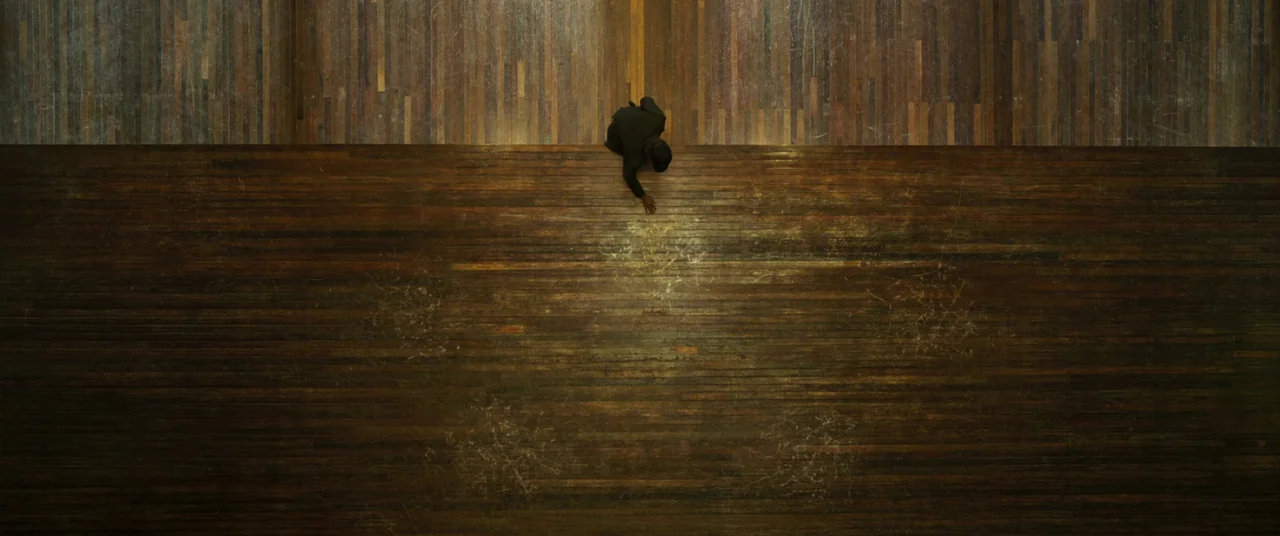 Swing Kids (2018) movie still: wide — A large rectangular room features polished dark wood plank flooring with visible scuff marks. A man kneels at…