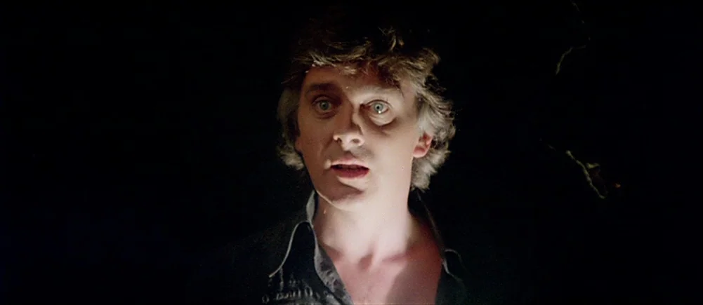 Deep Red (1975) movie still: closeup — A man's face is illuminated from the front against a completely dark, featureless backdrop. He looks ahead…