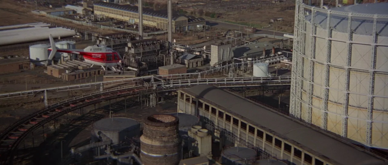 For Your Eyes Only (1981) movie still: establishing — A vast industrial complex features numerous storage tanks, metallic piping, and large factory…