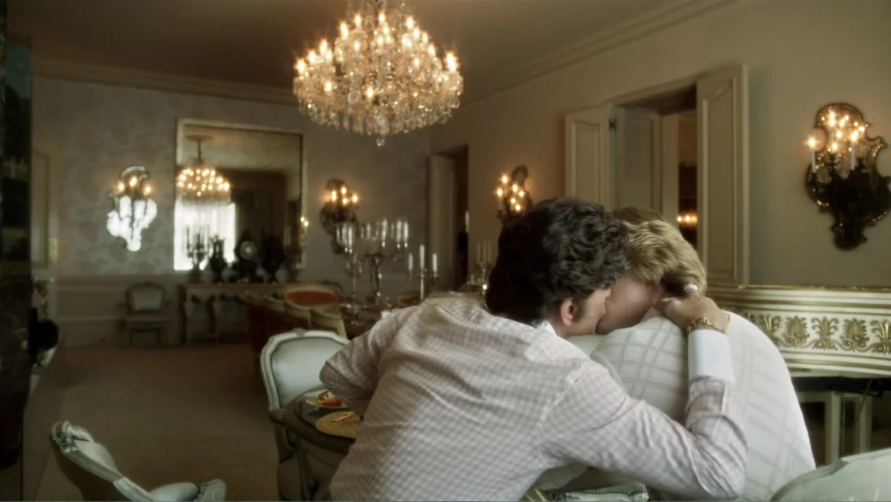 Behind the Candelabra (2013) movie still: medium — A formal dining room features crystal chandeliers, ornate gold furniture, and light beige walls.…