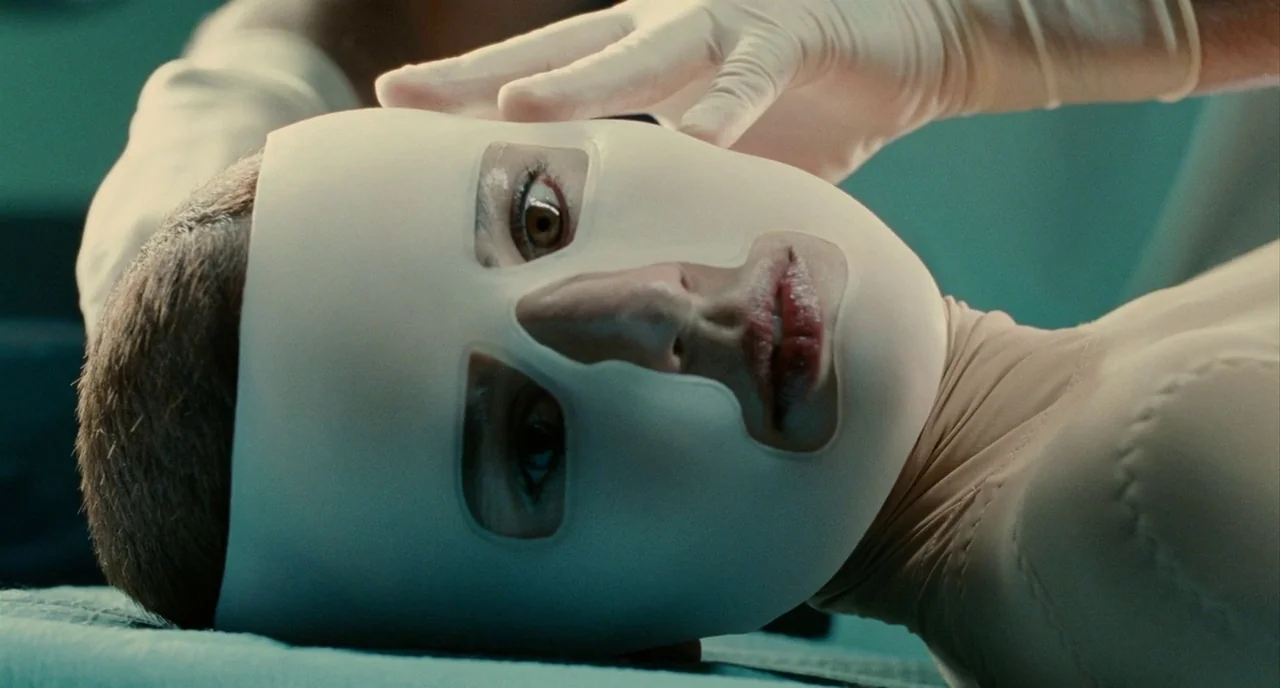The Skin I Live In (2011) movie still: closeup — A medical setting with sterile tones and cool lighting. A woman lies flat wearing a tight mask…