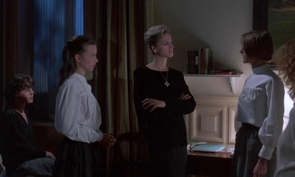 Phenomena (1985) movie still: medium — A domestic interior space features four women gathered together in a dimly lit room. The subjects occupy the…