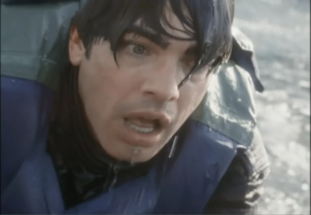 White Mile (1994) movie still: closeup — A man is in the middle of open water wearing a blue life vest. He has wet hair and a shocked expression…