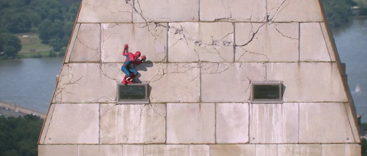 Spider Man: Homecoming (2017) movie still: wide — A tall stone monument exterior with cracked masonry and small rectangular glass windows. A…