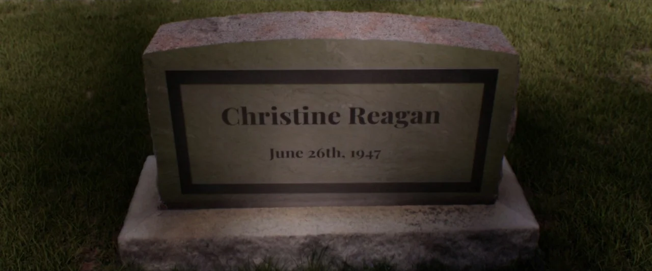 Reagan (2024) movie still: closeup — A stone grave marker is embedded into a patch of green lawn. The inscription reads Christine Reagan and the…