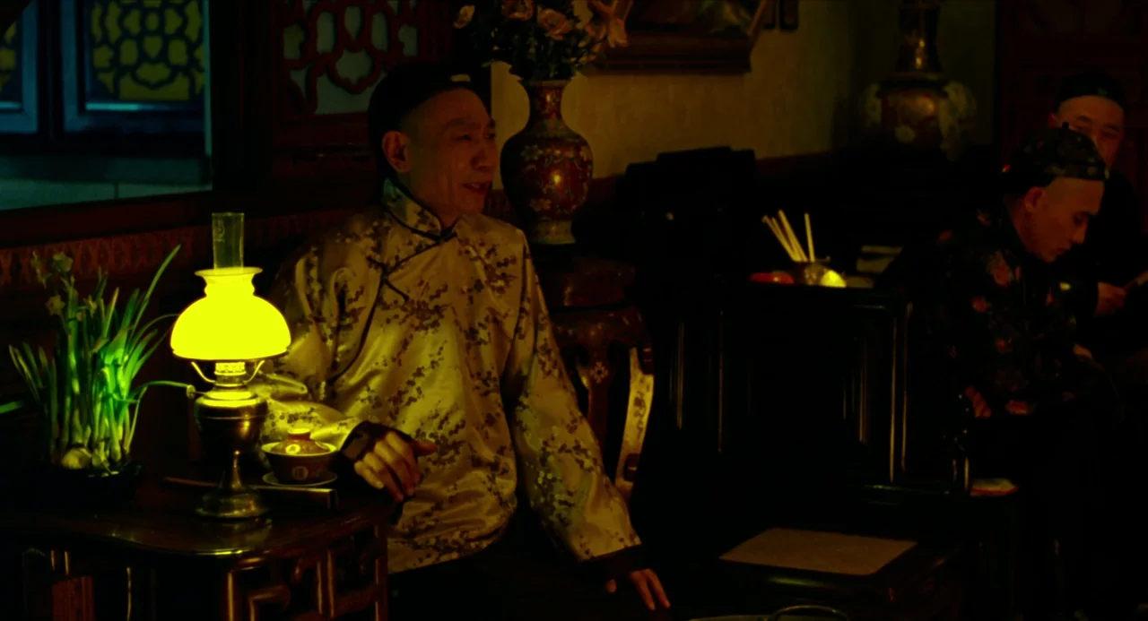 Flowers of Shanghai (1998) movie still: medium — A traditional room features dark wooden furniture, a decorative vase, and a glowing table lamp. A…
