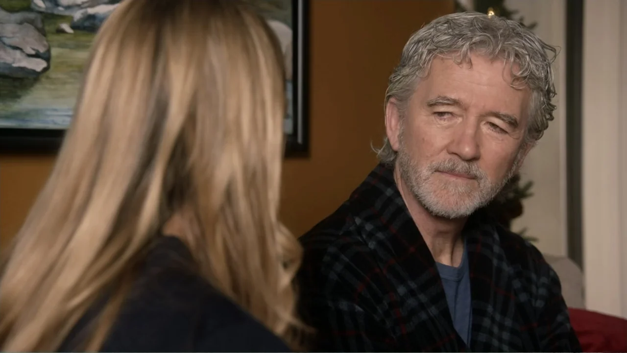 The Christmas Cure (2017) movie still: medium — A domestic indoor setting features a man and a woman in conversation. The man sits while looking at…