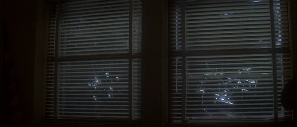 Assault on Precinct 13 (1976) movie still: wide — Two large windows covered by closed horizontal blinds occupy the center of the frame. Bright light…