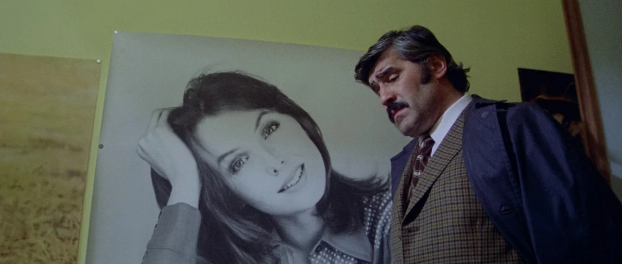 What Have They Done To Your Daughters? (1974) movie still: medium — A room with olive-green walls features a large monochrome poster of a smiling…