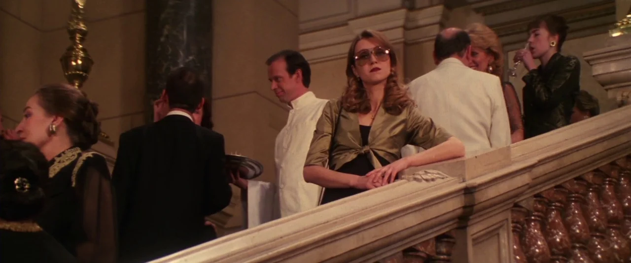 Mission: Impossible (1996) movie still: medium — An opulent interior staircase features ornate stone balustrades and marble accents. A woman in a…