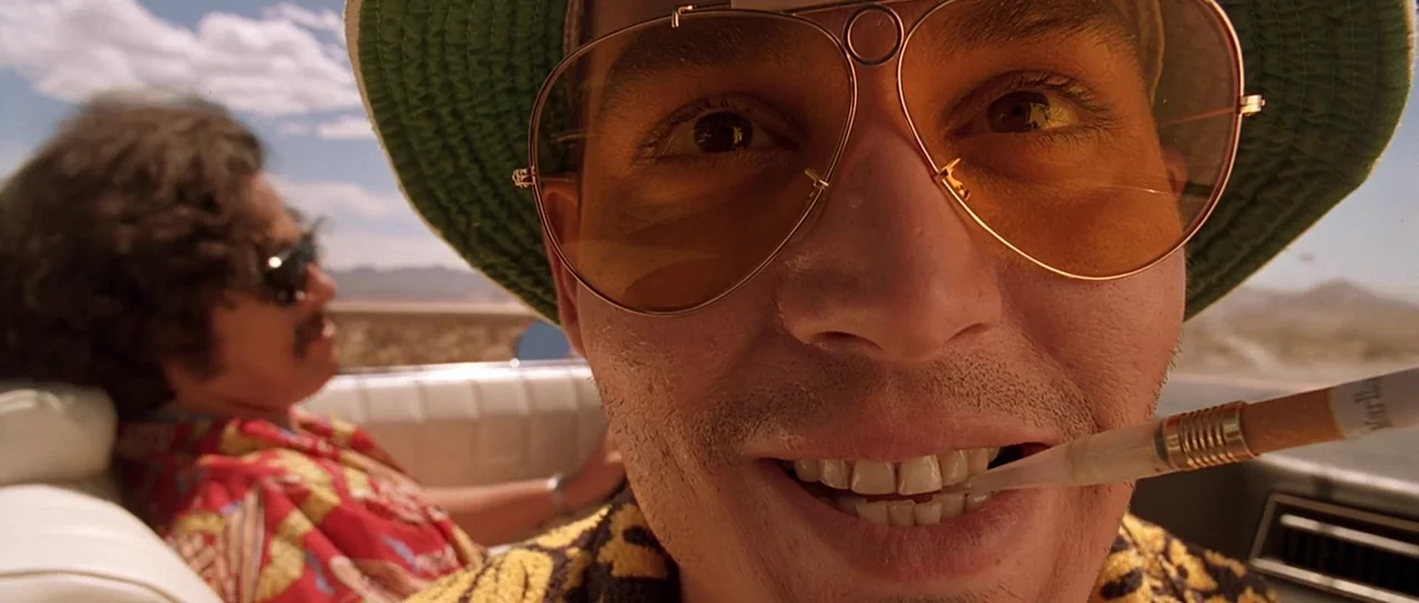 Fear and Loathing In Las Vegas (1998) movie still: closeup — A man drives a convertible car through a bright, sunlit desert landscape. The driver…