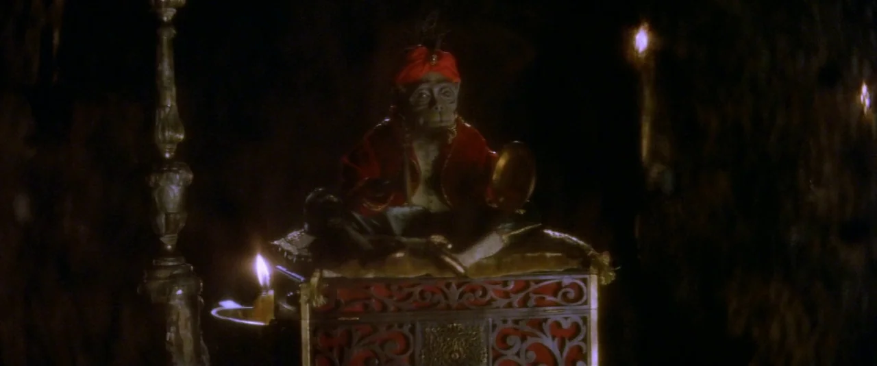 The Phantom of the Opera (2004) movie still: medium — A small monkey sits perched atop a decorative, carved box inside a dark environment. The…