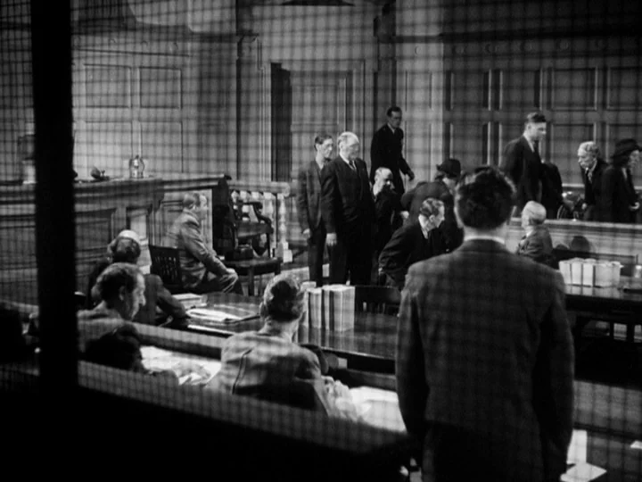Stranger on the Third Floor (1940) movie still: wide — A wood-paneled room features rows of benches and a central table with books. People in suits…