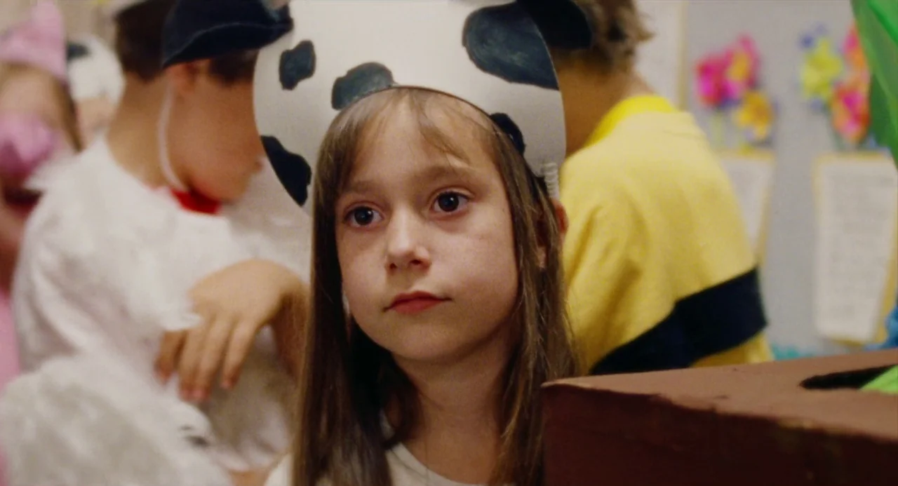 Mr. Roosevelt (2017) movie still: closeup — A group of children stand in an indoor space decorated with colorful paper craft. A young girl in the…